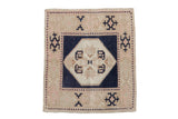 Distressed vintage Oushak square rug with a navy blue geometric medallion, ivory center, and sand-pink field.