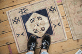 Vintage Oushak rug mat with a navy and pink geometric pattern, shown for scale.