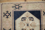 Evenly worn texture on a vintage Oushak mat with navy, pink, and sand geometric motifs.