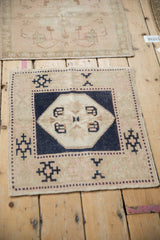 Vintage Oushak square mat in navy and sand, shown alongside another distressed mini rug.
