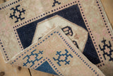 A folded corner of the distressed Oushak mat reveals its pliable hand-knotted weave and low pile.