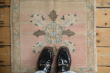 Distressed texture of dusty rose Oushak rug with charcoal and sky blue quatrefoil details.