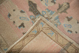 Textured distressed Oushak rug pile in dusty rose, ivory, sky blue, with intact selvage.