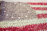 Knotted folk American Flag rag rug, with muted tones, sewn stars, and visible fraying.
