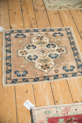 Distressed Oushak rug corner with even wear, showing cobalt blue vine border, beige floral elements.