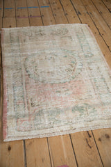 Texture of distressed Oushak square rug, showing wear to foundation, muted rose and sea foam green.