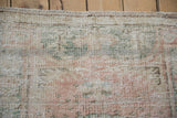 Distressed pile texture of vintage Oushak rug with faded rose, olive green, and blush tones.