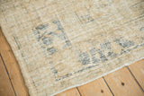 Distressed Oushak carpet corner, worn beige pile with slate blue border and selvage.