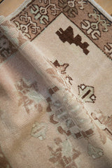 Soft, distressed pile texture of a vintage Oushak rug, featuring muted plant motifs.