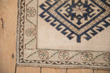 Distressed vintage Oushak rug corner, showing low pile, cobalt blue gul, and meandering vine border.