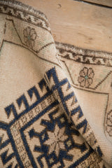Distressed Oushak rug pile texture, featuring geometric blue and beige motifs.