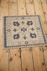Vintage Oushak square mat with a central diamond medallion, viewed from a high angle.