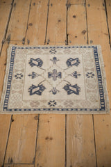 Vintage Turkish Oushak mat showing even, distressed wear on its ivory field and dusty navy blue medallion.