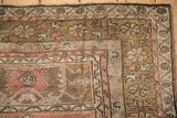 Distressed Anatolian rug corner showing blush, bronze serrated floral blossoms and secure selvage.