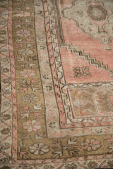 Close-up of distressed blush and bronze serrated floral border on vintage Anatolian rug.