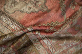 Textured pile and faded blush, bronze serrated leaf floral patterns on a vintage Anatolian rug.