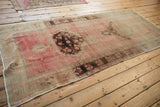 Secure edge and distressed pile of a vintage Oushak runner in soft rose and beige.