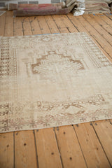 Distressed Oushak rug detail with geometric medallion, pomegranate border, and worn ivory pile.