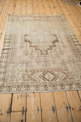 Distressed ivory and chocolate brown Oushak rug displaying geometric medallion and seed blossoms.