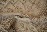 Distressed hand-knotted Oushak rug pile texture with faded beige and ivory patterns.