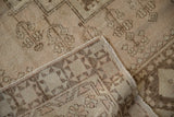 Folded distressed Oushak rug, showing ivory, beige geometric pile and woven foundation.