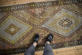 Distressed vintage Oushak runner with worn texture, faded copper, gold, and blue motifs.