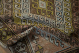 Textured corner of a distressed Oushak runner with copper, gold, and blue geometric motifs.