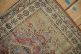 Distressed vintage Oushak rug corner: worn pile, jade green field, and diverse floral border.