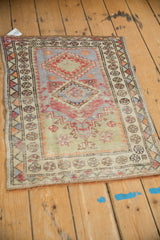 Distressed Oushak rug showing top mehrab with hook and latch florals in pale blue and red.