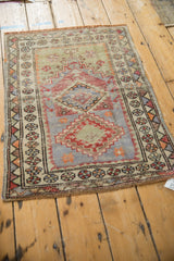Distressed Oushak rug's bottom corner with a diamond motif and faded floral pinwheel border.