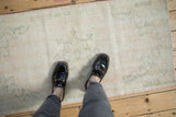 Vintage distressed Oushak runner showing worn pile texture with cream, beige, and rose hues.