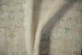 Distressed cream and beige pile texture on the vintage Oushak rug, showing wear.