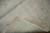 Distressed vintage Oushak rug corner, with faded pile, woven foundation, and pink selvage.