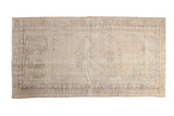 Vintage distressed Oushak rug runner with faded cream ground, subtle blue medallion, 2'6