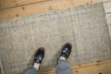 Worn pile of vintage distressed Oushak runner with faded blue scrolling vines on antique ivory.