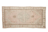 Distressed Oushak rug runner, dusty rose and cream medallion with time-softened brown motifs.