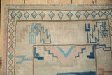 Distressed Oushak rug fringe and geometric border with blue and pink hook motifs.