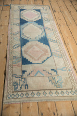 Distressed vintage Oushak runner edge, showing geometric patterns, cobalt blue, dusty pink, and side selvage.