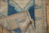 Distressed Oushak runner folded, showing hand-knotted construction, cobalt blue and pink geometric pattern.