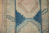 Detail of distressed Oushak runner texture, showing hand-knotted cobalt blue and dusty pink geometric motifs.
