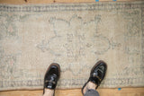 Distressed vintage Oushak rug runner showing worn pile, subtle patterns, and feet for scale.