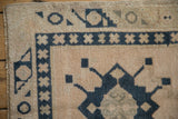 Distressed vintage Oushak rug corner with geometric motifs in dusty navy and cream.