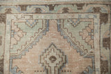 Faint foundation showing through distressed mauve, blue, and brown Oushak rug pile.