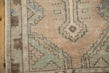 Distressed vintage Oushak rug edge with geometric pattern in mauve, slate blue, and beige.