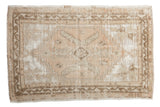 Vintage distressed Oushak rug in faded beige, brown, and white with central geometric medallion. 3'3