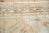 Distressed Oushak rug detail showcasing foundation through worn beige, sandalwood, and white patterns.