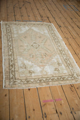 Oushak rug corner, distressed beige field, geometric brown border with serrated motifs.