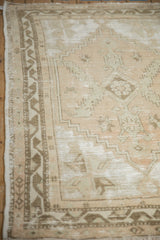Distressed Oushak rug detail showing worn geometric patterns in beige and sandalwood.