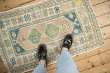 Small vintage Oushak rug with soft geometric patterns in blue, green, and sandalwood for scale.