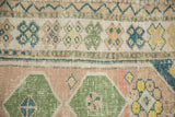 Simplistic geometric floral motifs and a zig-zag vine border on a distressed Oushak rug.